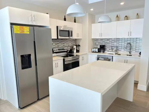 een keuken met witte kasten en een roestvrijstalen koelkast bij Coral Beach 204 - by ZenBreak in Saint Peter