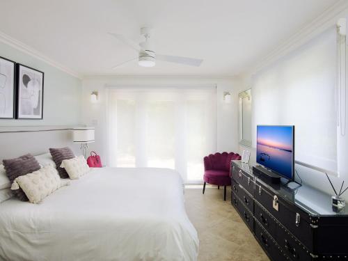 una camera con letto bianco e TV su un comò di KingsGate 1 - by ZenBreak a Saint Peter