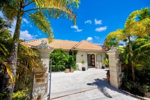 a house with a gate and palm trees at Kyalami - by ZenBreak in Saint James