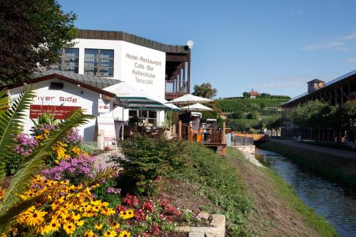 a building next to a river with flowers at Mercure Hotel Bad Duerkheim An Den Salinen in Bad Dürkheim