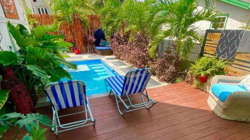 two blue chairs sitting next to a swimming pool at Villa De Lasannta - by ZenBreak in Christ Church