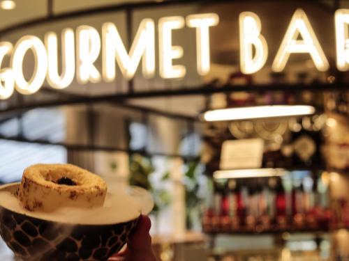 eine Person, die einen Teller mit einem Donut darauf hält in der Unterkunft Novotel Campo De Las Naciones in Madrid