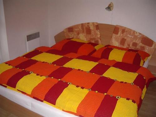 un letto con una coperta arancione e gialla sopra di Apartment Spiezovec 42 Donovaly a Donovaly