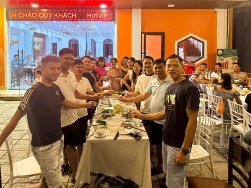 un gruppo di persone che si trovano intorno a un tavolo con cibo di TGlobal Quynh Hoa Tam Dao a Tam Ðảo