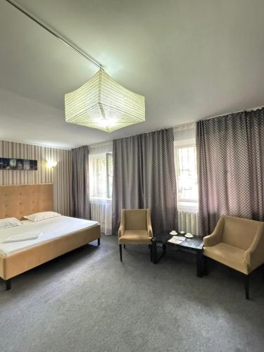 a bedroom with a large bed and two chairs at BT City Hotel in Gornyy Gigant