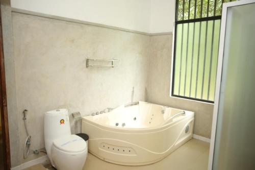 a white bathroom with a tub and a toilet at Nil Diya Mankada Safari Lodge in Udawalawe