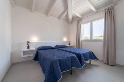 2 letti in una camera bianca con lenzuola blu di Luxi by NG Collection a Olbia