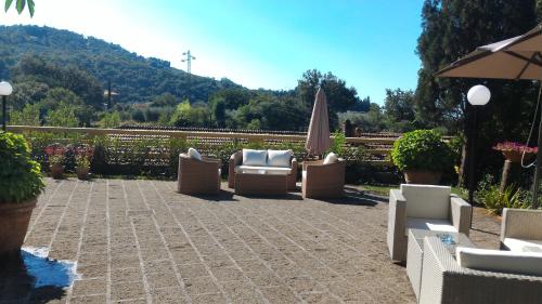 a patio with a bunch of chairs and an umbrella at Villa La Nussa in Capolona