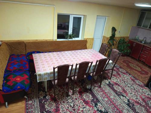 Ein Tisch und Stühle in einem Wohnzimmer mit einem Tisch und einem Teppich in der Unterkunft Гостевой дом Куттуу Кол in Kichi-Jargylchak