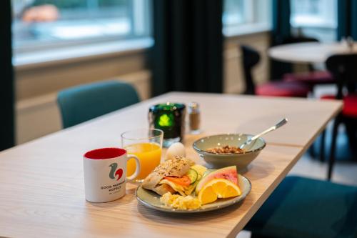 einen Tisch mit einem Teller Essen und einer Tasse Orangensaft in der Unterkunft Good Morning Sollentuna in Sollentuna