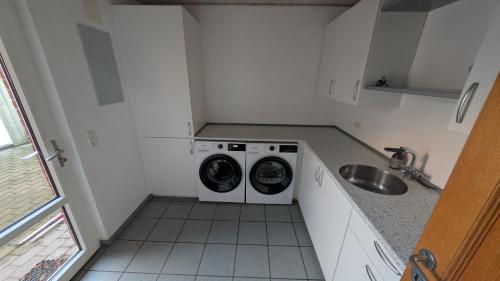 una piccola cucina con lavatrice e lavandino di Villa Henneby a Henne