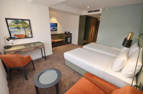 a hotel room with a white bed and a desk at Hotel Aleksandar Conference & Spa in Žabljak