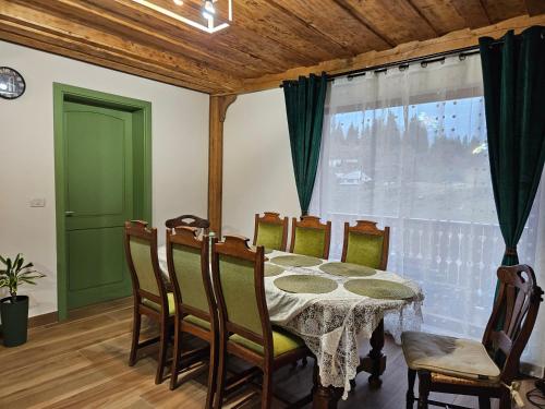 een eetkamer met een tafel en stoelen en een raam bij Casa din fagi in Munună