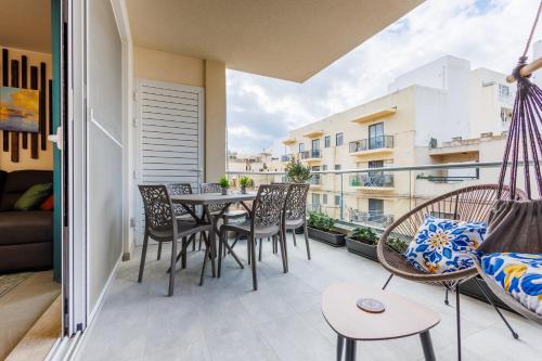 a patio with a table and chairs on a balcony at Stylish 2BR Retreat, Central Location, Few Steps from the Sea by QuickTrips in Marsaskala