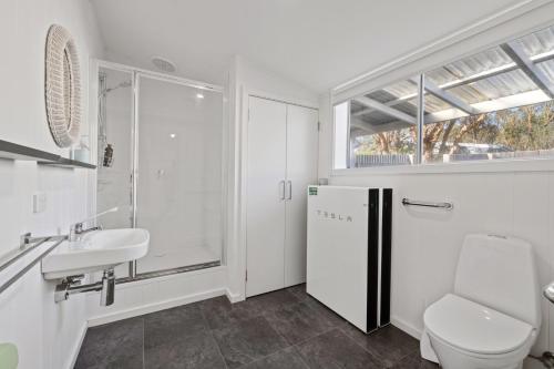 a white bathroom with a sink and a refrigerator at Wombat Pavilion in Yanakie