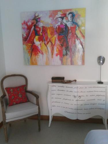 a painting on the wall above a dresser and a chair at Blue Garden Yogyakarta in Yogyakarta