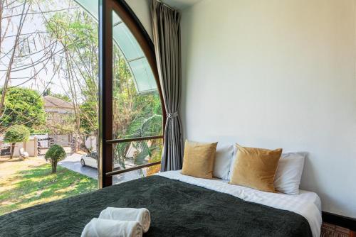 una camera da letto con un letto con una grande finestra di Bangkok Cozy Garden Pool Villa Sukhumvit a Amphoe Phra Khanong