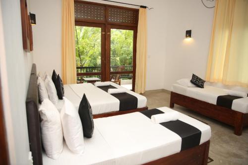a room with three beds and a window at Nil Diya Mankada Safari Lodge in Udawalawe