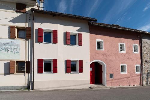 a red and white building with red shutters at Corte Maccarini - Appartamento Venezia - Dotato di corte interna privata in Mel