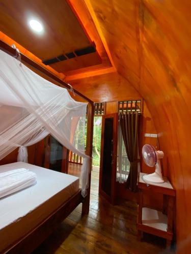 a bedroom with a bed and a lamp in a room at Batu Katak Jungle River & Trekking in Bukit Lawang