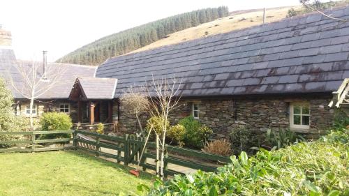 a stone house with a wooden fence in front of it at Clarisses Cottage in Laragh
