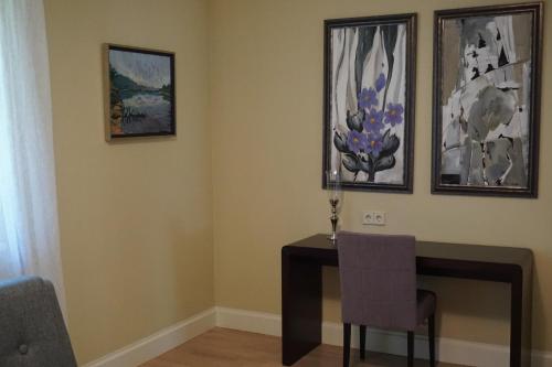 a room with a table and a chair and paintings at Wooden Villa APARTMENTS in Jūrmala