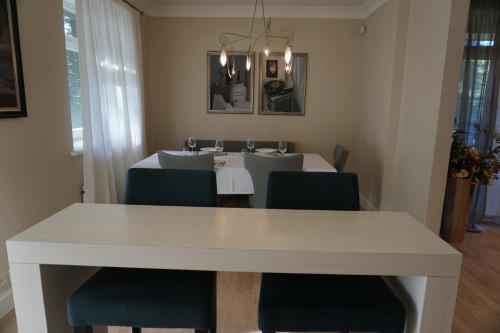 a dining room with a white table and blue chairs at Wooden Villa APARTMENTS in Jūrmala