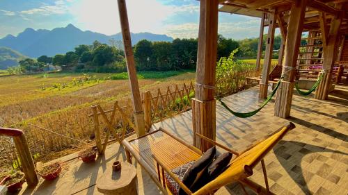 a porch with a hammock and a view of a farm at Meadow Mai Chau Homestay in Mai Chau