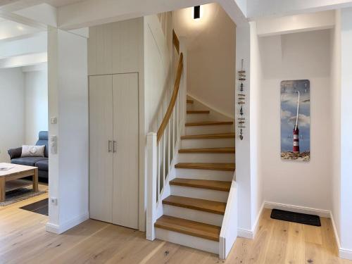 een trap in een huis met een schilderij van een vuurtoren aan de muur bij Haus Dünenperle, Ferienwohnung Wanderdüne in Wittdün