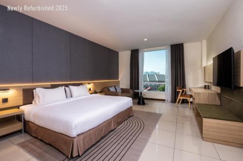 Una habitación de hotel con una cama grande y un televisor. en One Pacific Hotel and Serviced Apartments, en George Town