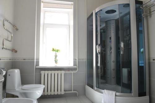 a bathroom with a shower and a toilet and a window at Altyn Dala Hotel in Astana