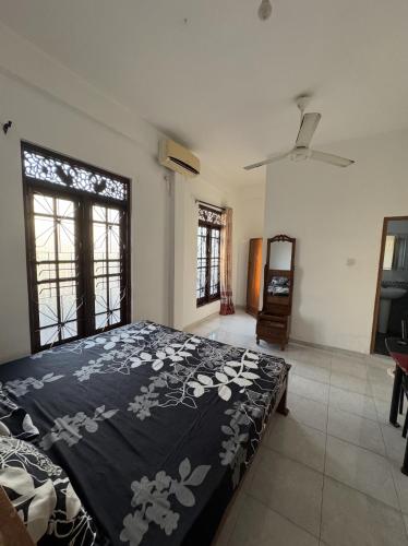 a bedroom with a bed with a black blanket with flowers at Lanka Hotel in Mirissa