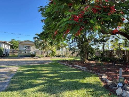 a tree with red flowers in a yard at Bushchooks Travellers Village in Bororen