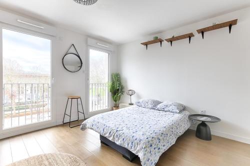 een witte slaapkamer met een bed en een groot raam bij Ellington - Studio dans le quartier daffaires in Chatou