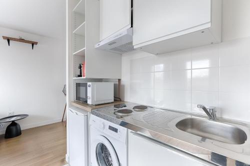 een witte keuken met een wastafel en een wasmachine bij Ellington - Studio dans le quartier daffaires in Chatou