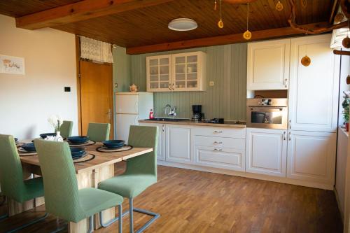 een keuken met een houten tafel en groene stoelen bij Kopitnik cosy cabin in Dol pri Hrastniku