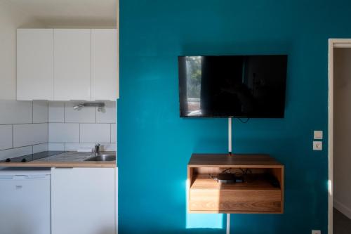 eine Küche mit einer blauen Wand und einem Fernseher an der Wand in der Unterkunft Kokoro - Parking in Ramonville-Saint-Agne