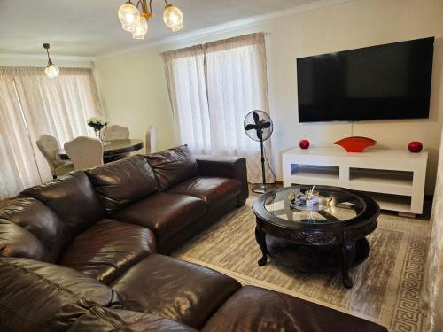 a living room with a leather couch and a coffee table at Hillcrest Cosy Cottage in Hillcrest