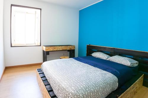 a bedroom with a bed with a blue wall at The Pallet - Guest House in Santa Cruz