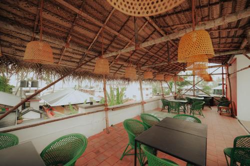 un restaurante con sillas verdes, mesas y luces en Native by Cliff and Coral, en Varkala