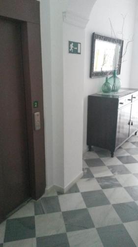 a room with a checkered floor and a door with a window at Hostal Centro Sol in Cádiz
