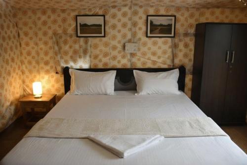 a bedroom with a large white bed with two pillows at Araku Mountview Camping Resort in Araku