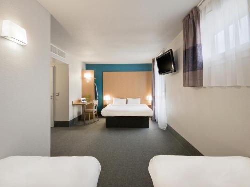 a hotel room with two beds and a tv at B&B HOTEL Grenoble Centre Alpexpo in Grenoble