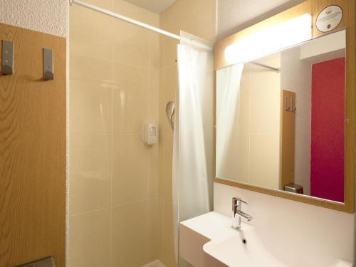 a bathroom with a sink and a shower with a mirror at B&B HOTEL Grenoble Centre Alpexpo in Grenoble