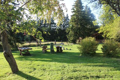 a park with benches and picnic tables in the grass at Pilsberģu krogs in Jūrkalne