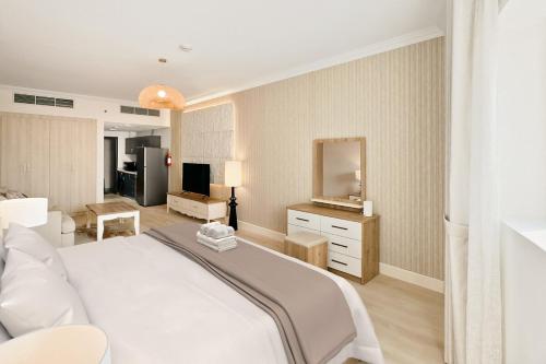 a bedroom with a white bed and a living room at Stylish Furnsihed Apartments Opposite Five Hotel In JVC in Dubai