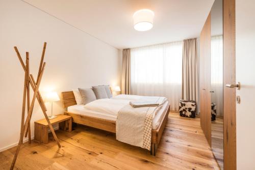 a white bedroom with a bed and a window at Andermatt Alpine Apartments in Andermatt