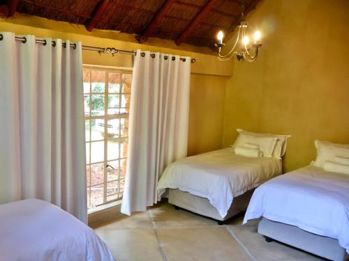 een slaapkamer met 2 bedden en een raam met gordijnen bij Winnaarspoort Lodge in Hydro