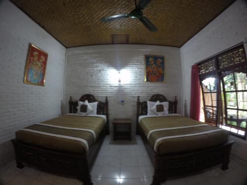 a bedroom with two beds and a ceiling fan at Eka's Homestay in Ubud