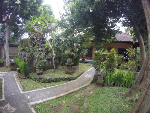 a garden in front of a house with trees at Eka's Homestay in Ubud